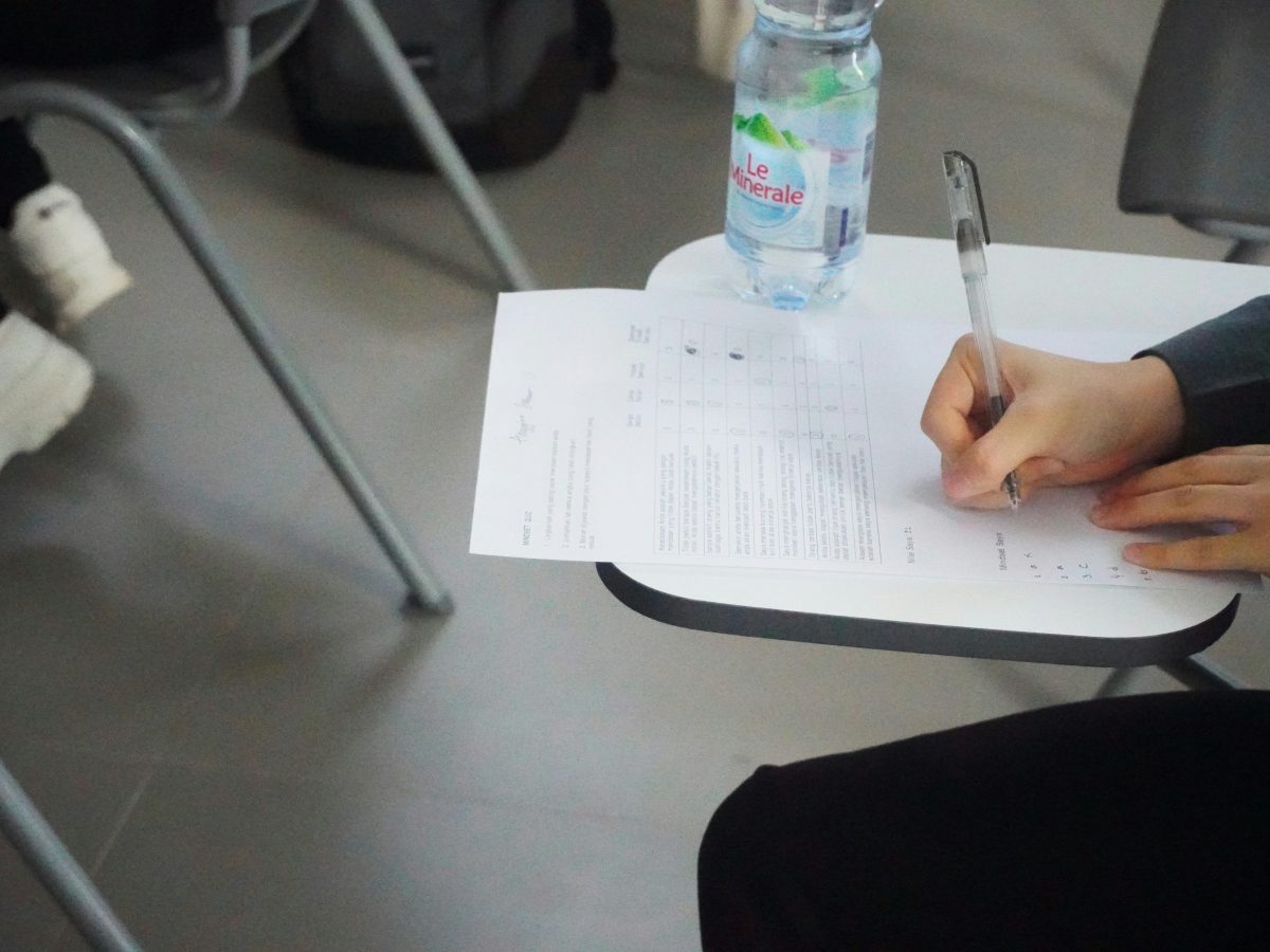 Person filling out a survey on a desk.