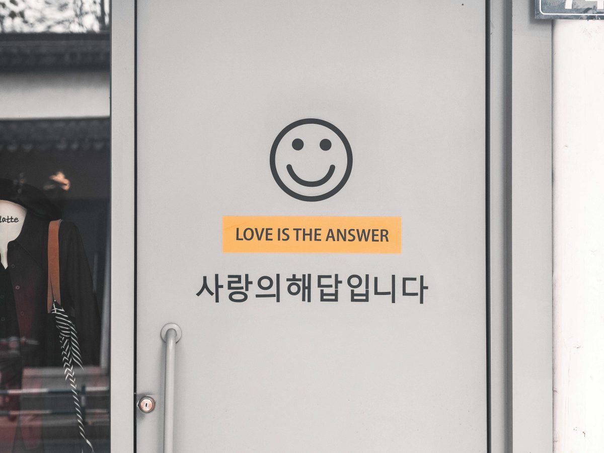 Imprint on a door shows a yellow smiley love with the text, 'love is the answer' below and with the Korean translation below