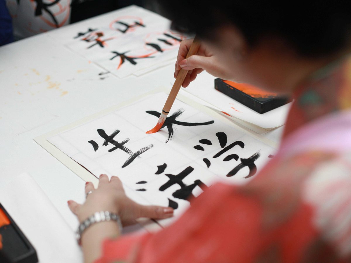 Person Holding Brush Drawing Kanji Script